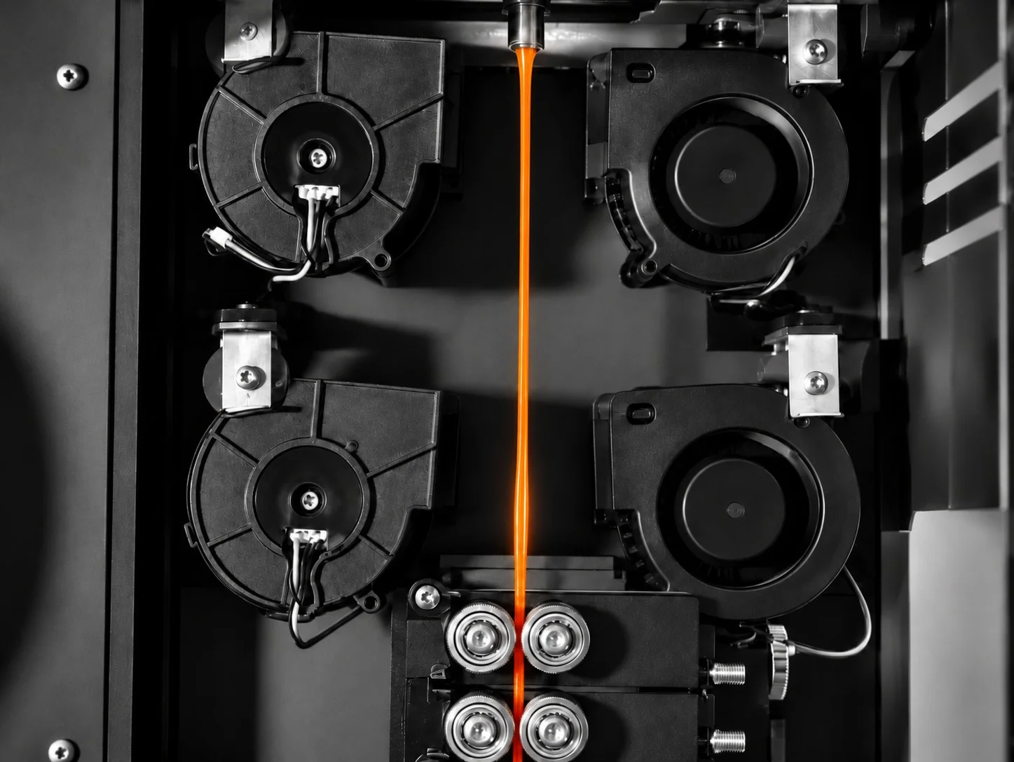 Orange filament strand leaving the die between cooling blowers