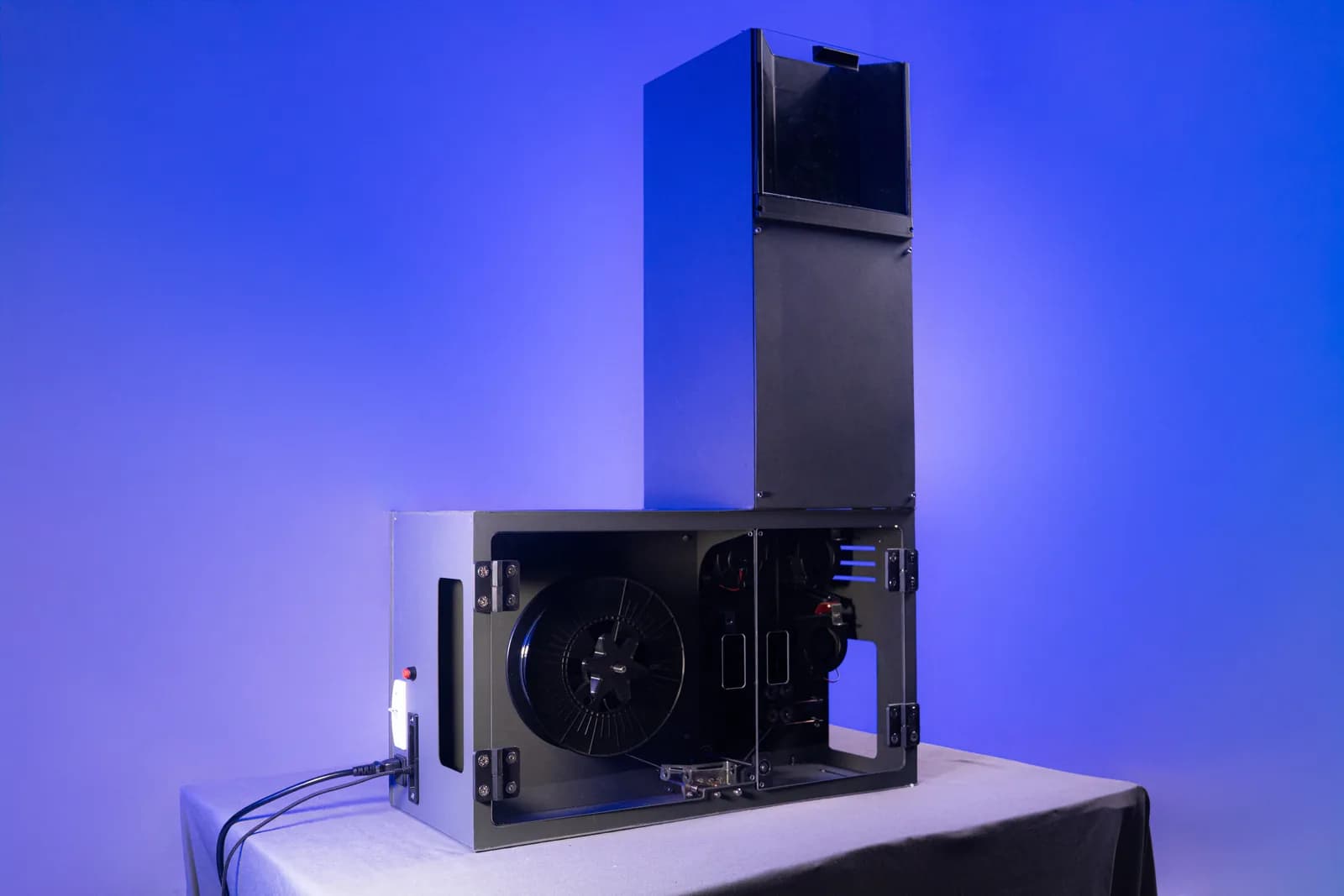 ASTER-C extruder showing the full column: hopper tower above, extrusion and spooling bay below