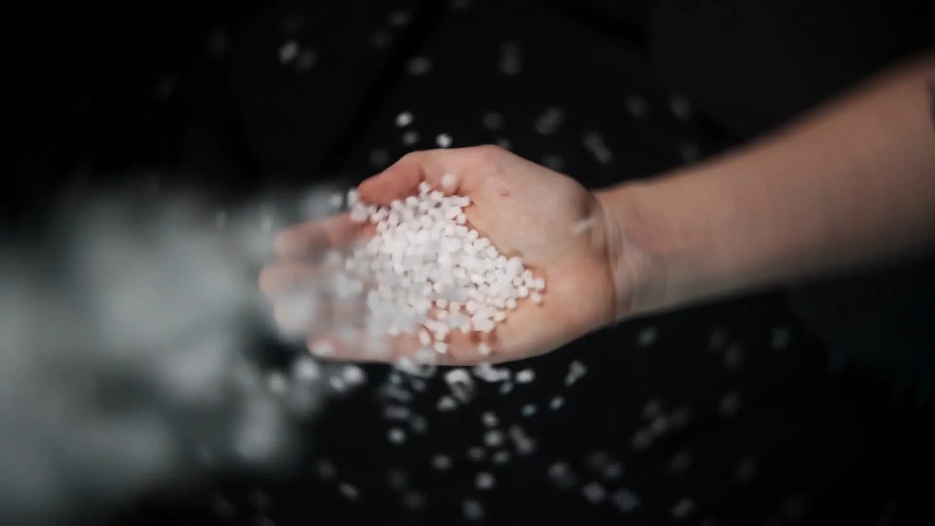 A handful of polymer pellets being poured, the raw feedstock ASTER-C extrudes into filament